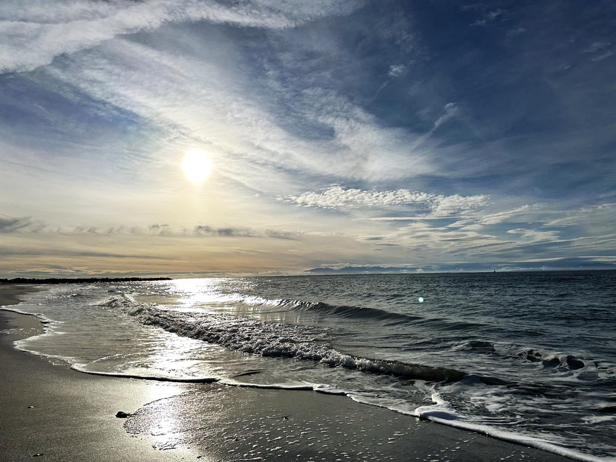 Waves rolling onto the shore at Wreck Beach during sunset.