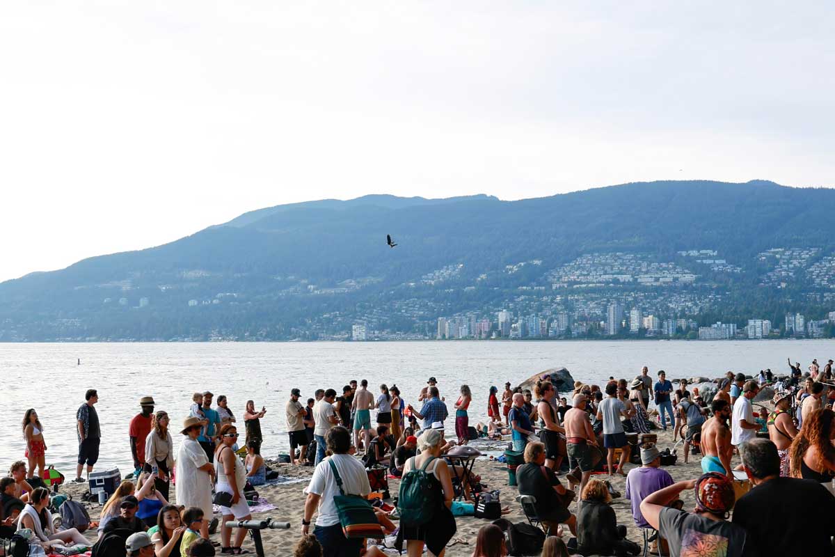 Crowd enjoying a lively drum circle at Third Beach, Vancouver.