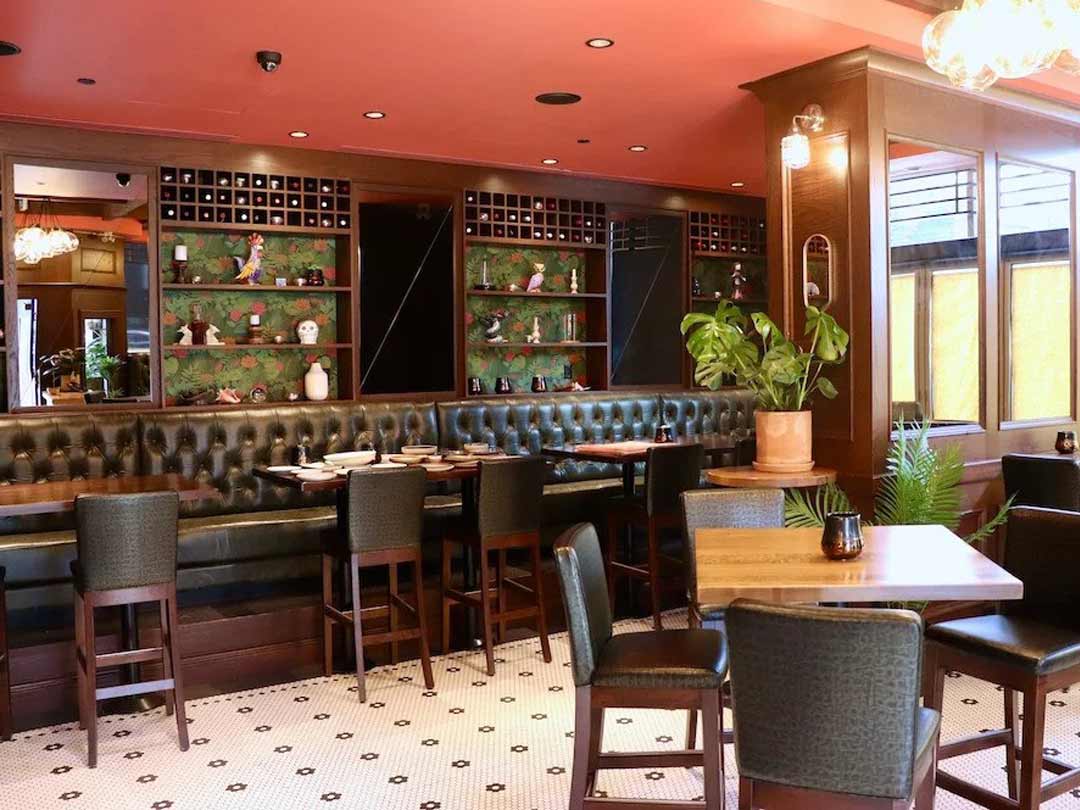 Bright dining area with green booths, patterned floor, & warm decor.