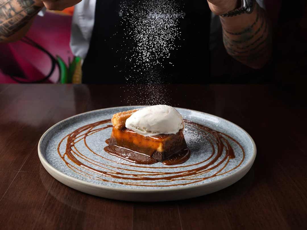 Sticky toffee pudding with ice cream and powdered sugar.