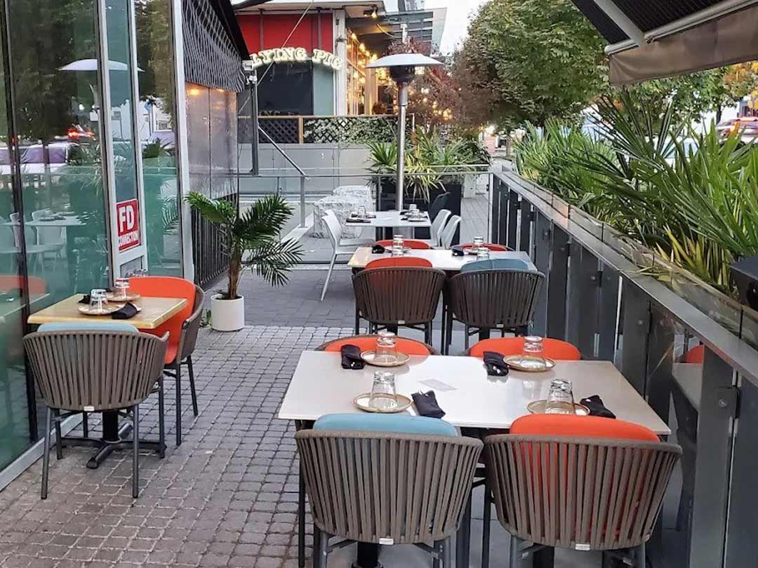 Cozy outdoor patio dining area with colorful chairs and plants.