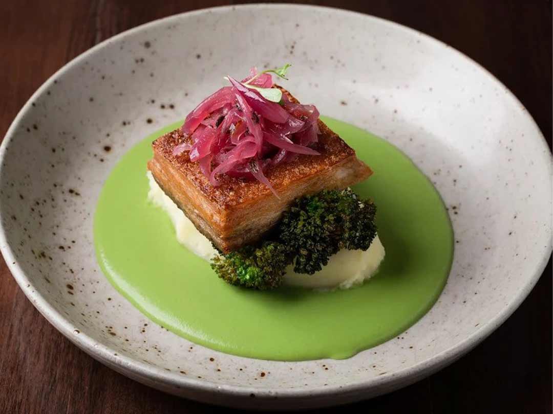 Crispy pork belly served with mashed potatoes and green sauce.