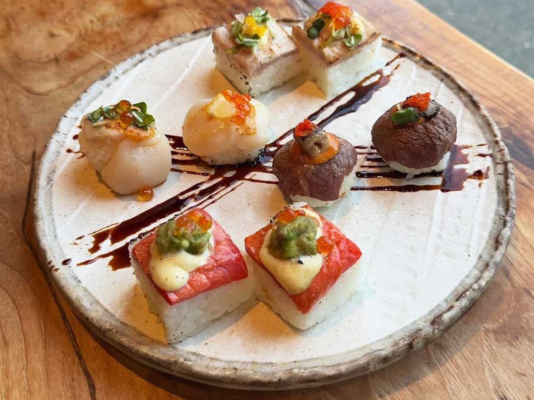 Assorted aburi sushi on a ceramic plate.